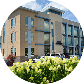 Modern office building with large windows and landscaped flower beds, representing professional and commercial spaces
