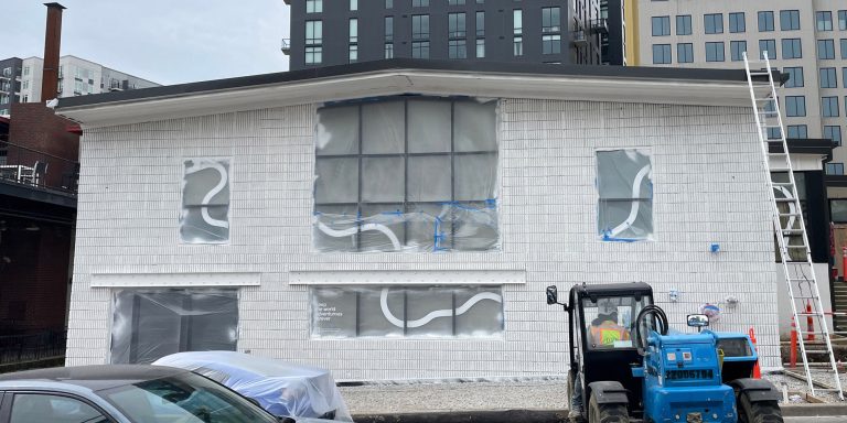 Exterior of the EV Automotive Showroom with an M2 Group worker operating construction equipment