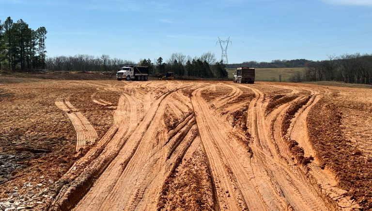 A construction site with red-tinged soil and equipment tracks at Idlewild Farms in Columbia, TN.