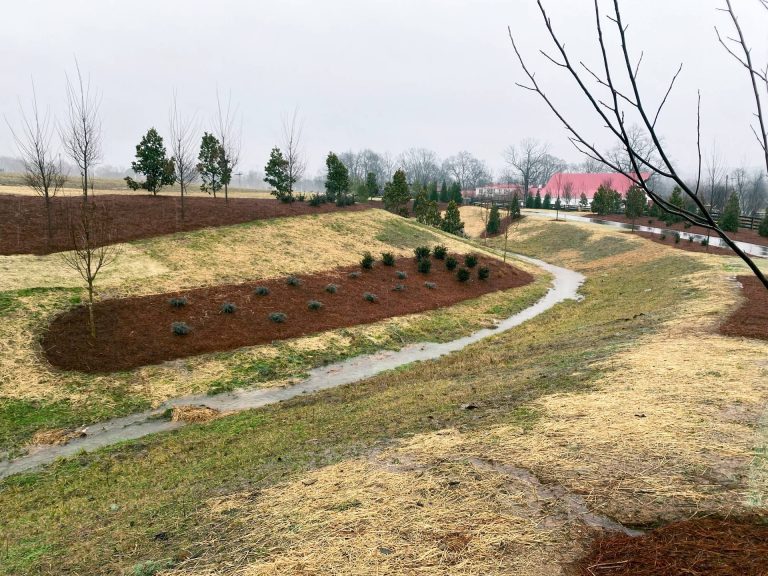 Grassy residential area with a water drain cutting through the property, part of the Luxury Residential Development project