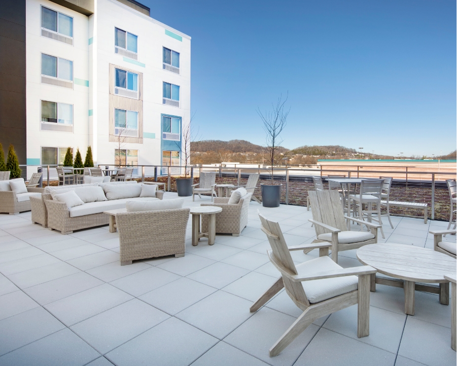 Outdoor rooftop seating area with a table, chairs, and casual couches for hospitality projects.