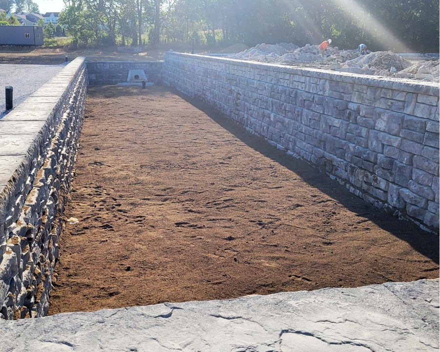 Dirt area with stonework and a visible pipe structure for water outflow, representing utility infrastructure projects.
