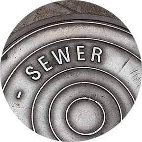 Close-up of a metal sewer cover, representing wastewater and sewer infrastructure